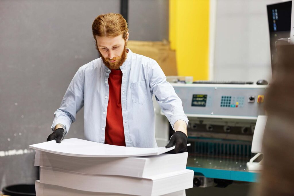 man-handling-paper-stacks-at-printing-factory-PEGZN2L.jpg
